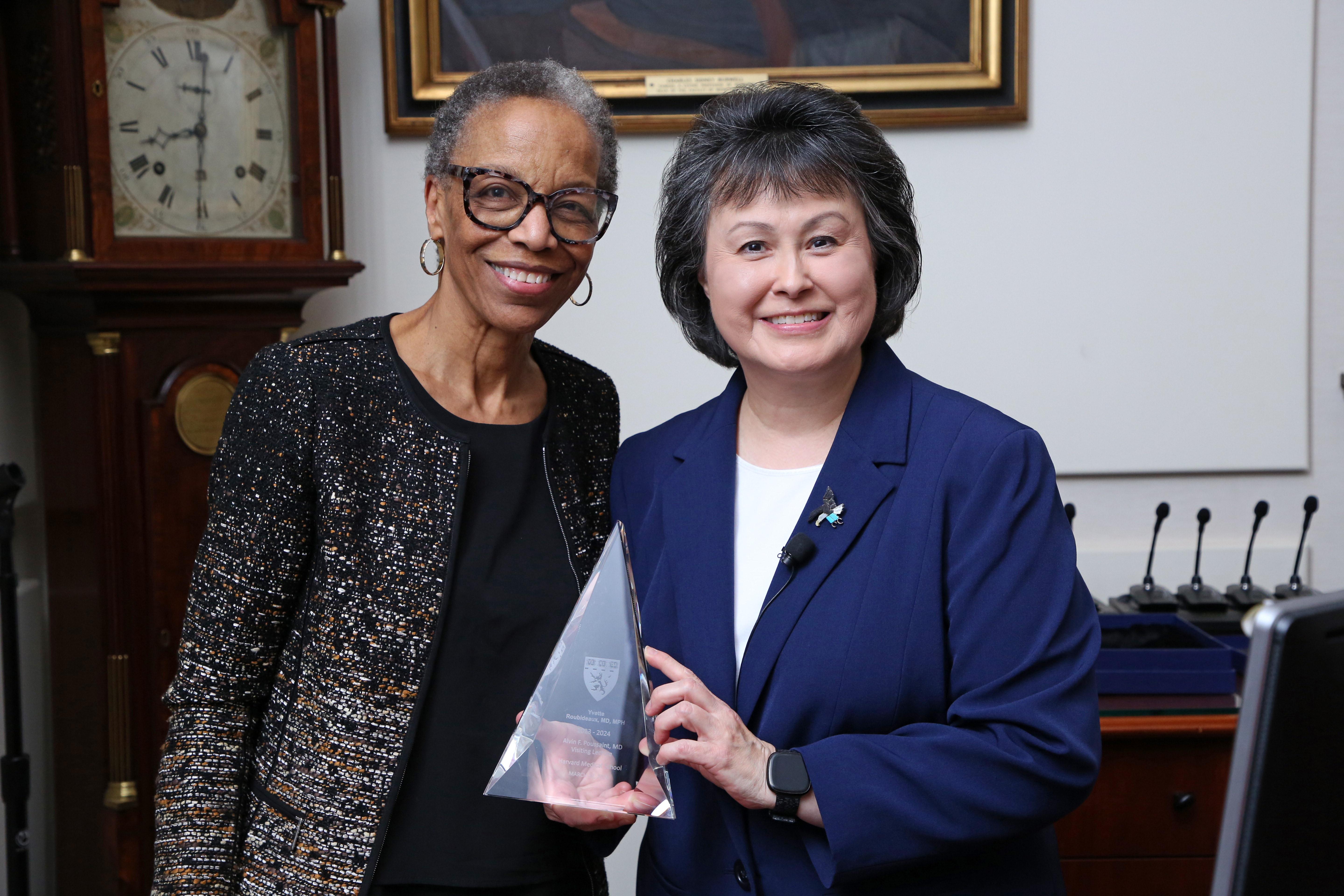 Yvette Roubideaux holds a triangular glass award and poses with Joan Reede.